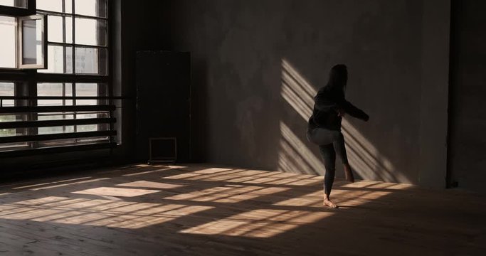 Enjoying modern dance. Girl dancing in studio with large windows and beautiful sunlight. Dance movement. Woman dancing contemporary freestyle. Sports, hobby and interests