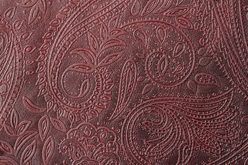 Texture of genuine leather close-up, burgundy color with embossed floral trend pattern, for wallpaper or banner design. For modern background