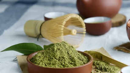 Green tea powder with leaf in ceramic dish on the table, Japanese wire whisk made of bamboo for matcha tea ceremony.