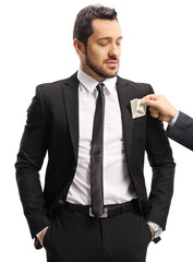 Male hand putting money into suit pocket of a businessman