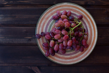 bunch of grapes on a plate on a dark wooden background.