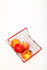 Miniature metal wire basket filled with ripe red eating apples isolated on a white background with space for copy