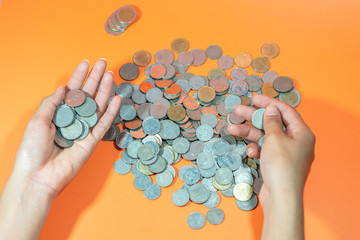 People count Thai baht currency on an orange background.