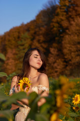 Beautiful lovely girl enjoying nature on a field of sunflowers. Sunlight plays on the field. Autumn time.