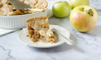 A traditional American apple pie decorated with stars and sugar, apples and cinnamon on a light...