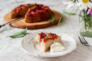 Sweet cake with caramelized plums, plums and a bouquet of flowers on the table. Rustic style.
