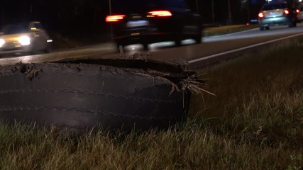 Blowout. Close up of exploded tire of semi truck on highway roadside at night.