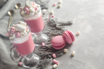 Pink hot chocolate winter drink with whipped cream and marshmallows. Macaroons and spoons. Copy Space