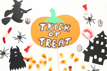 Text Trick or Treat with paper halloween decorations and candies on white background