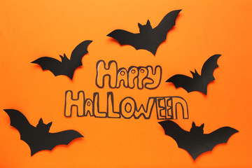 Paper bats with text Happy Halloween on orange background