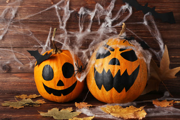 Halloween pumpkins with dry leafs and spiderweb on wooden background