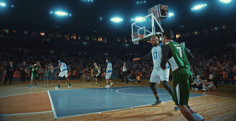 Basketball players on big professional arena during the game. Tense moment of the game. Celebration