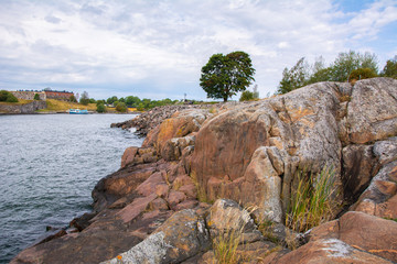 View of the rocky shore of Vallisaari island and Suomenlinna on the background, Helsinki, Finland