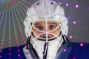 Detail of a male face in a white goalie hockey mask and  colorful lights.This is a detail hockey goalie. He is concentrated on game. He has colorful lights under his eyes.