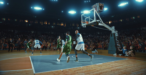 Basketball players on big professional arena during the game. Tense moment of the game. Celebration
