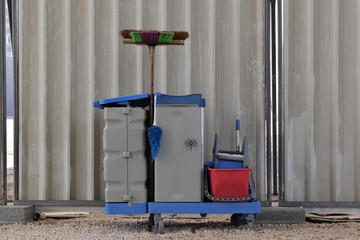 Cleaning tools cart waiting outside a building. All equipment in a single trolley for a professional cleaning service.