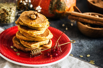 Homemade pancakes stacked on a red plate. Healthy pancakes made with coconut milk and banana, decorated with nuts and fresh berries. Sweet Homemade Stack of Pancakes with Syrup for Breakfast