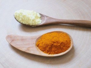 Sulfur powder and turmeric powder in wooden spoon.