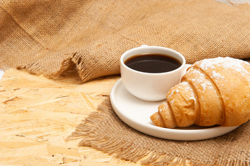 Croissant with a cup of coffee on a plate
