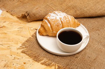 Croissant with a cup of coffee on a plate