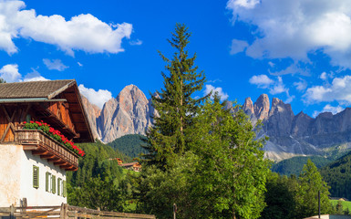 Fototapeta na wymiar Val di Funes, South Tyrol / Italy. Traditional alpine house with flowered balcony with the Dolomites in the background