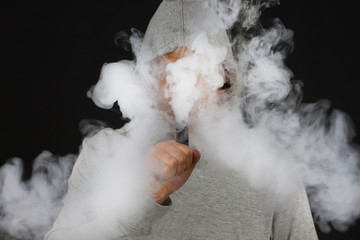 vaping man holding a mod cloud of vapor Black background isolated Selective focus