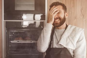 surprised man standing near the oven with burnt croissants.