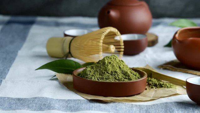 Green tea powder with leaf in ceramic dish on the table, Japanese wire whisk made of bamboo for matcha tea ceremony.