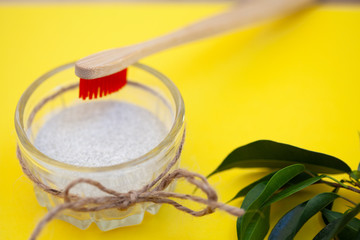 Wooden brushes, tooth powder, on a yellow background. Zero waste concept, close up.