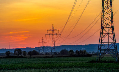 High voltage electricity pylons and transmission power lines on the blue sky background.