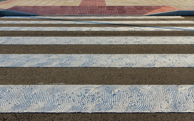 Detail of Zebra crossing for pedestrians painted on asphalt and roughened to avoid slipping 