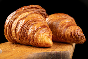 Tasty fresh croissant on a dark breadboard. Prepared bread on the kitchen table.