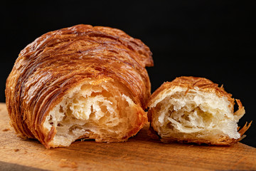 Tasty fresh croissant on a dark breadboard. Prepared bread on the kitchen table.