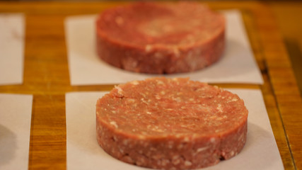 Multiple raw burger patties organized on a wooden board