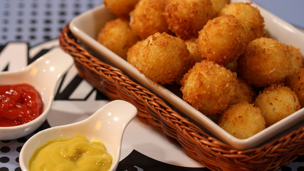 Delicious crispy cheese balls served with ketchup and mustard close up