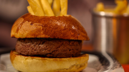 Conceptual fondue hamburger with fries dipped inside close up