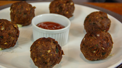 Big fried meatballs served with ketchup sauce close up