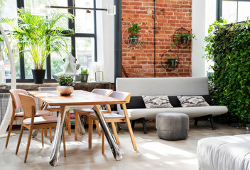 modern interior of living room  with a table and chairs and sofa. Wall with red bricks in industrial style. Loft apartment.