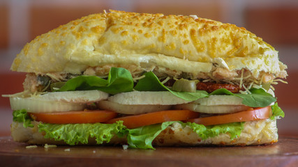 Long sandwich with chicken, lettuce, tomato and olives close up