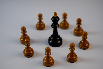 Chess pieces, black king surrounded by white pawns