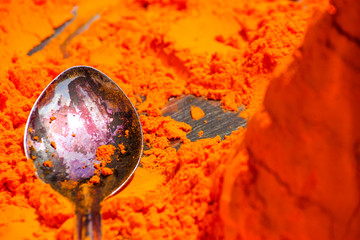 macro shot of a spoon in a pile of orange pigment in the city of Pushkar in India