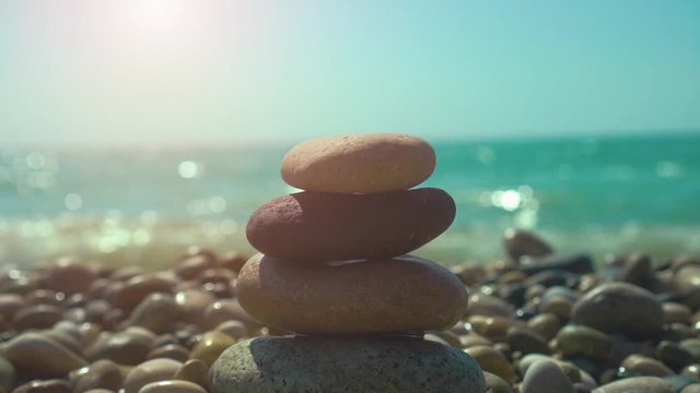Hand building stones pyramid on pebble beach, stability, zen, harmony, balance concept