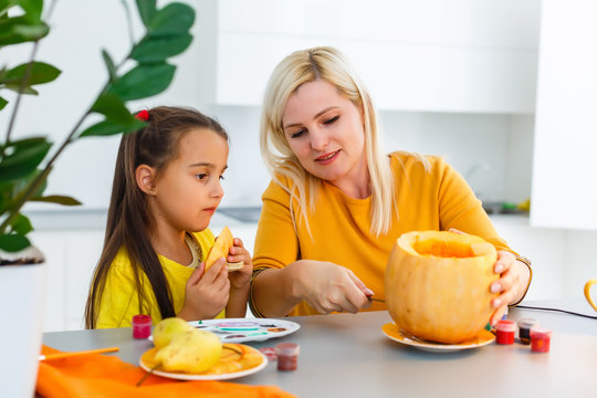 Mother and daughter carving pumpkin in the kitchen