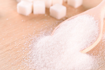 White cane sugar on a light wooden background