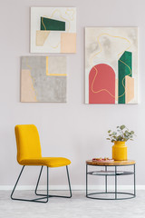 Yellow chair next to wooden coffee table with flowers in vase