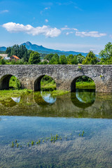 Fototapeta na wymiar Old stone bridge (Marmont bridge) on river Zagorska Mreznica, near Ogulin, Croatia, sunny summer day