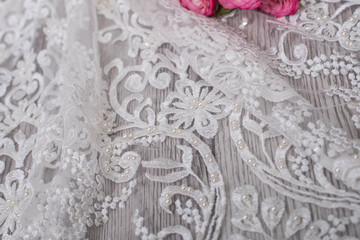 White wooden background with white spring flowers roses and lace ribbon. Happy womans day. The texture of lace on wooden background.