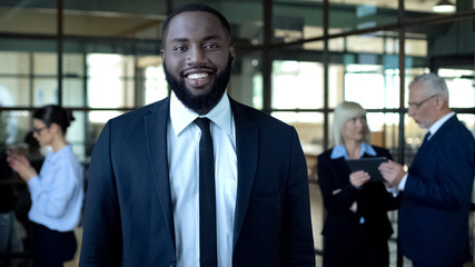 Black businessman smiling at camera, corporate success, career development