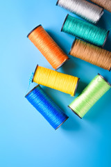  Colored thread coils on blue background, sewing, place for text