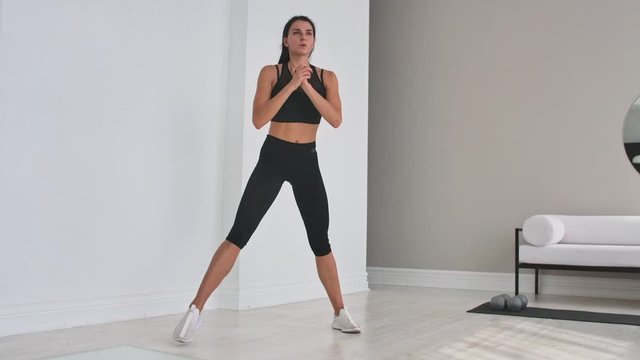Beautiful Fit Girl Doing Home Workout Performing Lateral Lunges In A Sitting Room.